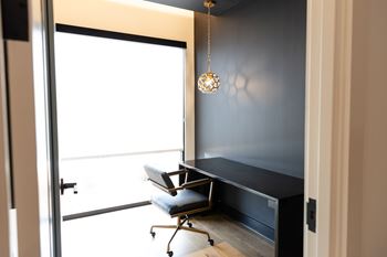 A black desk with a chair and a hanging light fixture at The Crest at South Point Apartments, Davenport , Georgia